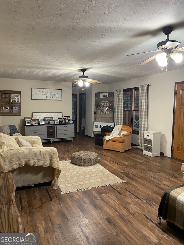 living room with a textured ceiling, dark hardwood / wood-style flooring, and ceiling fan