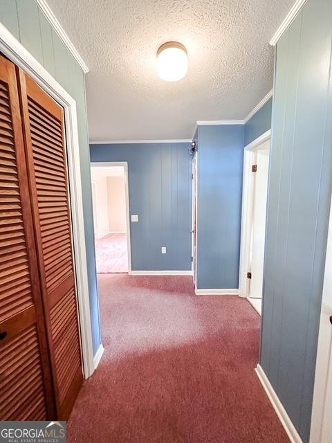 hall featuring carpet flooring, a textured ceiling, and ornamental molding