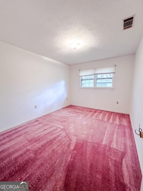 unfurnished room featuring carpet and a textured ceiling