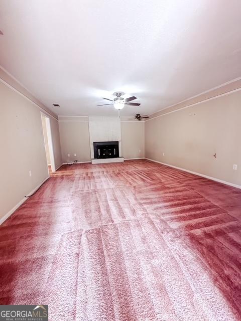 unfurnished living room featuring carpet flooring, ceiling fan, and ornamental molding