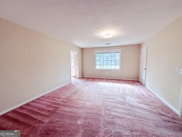 empty room featuring a textured ceiling and light carpet