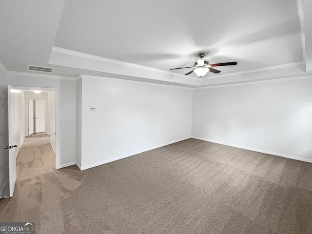 spare room with ceiling fan, ornamental molding, light carpet, and a tray ceiling