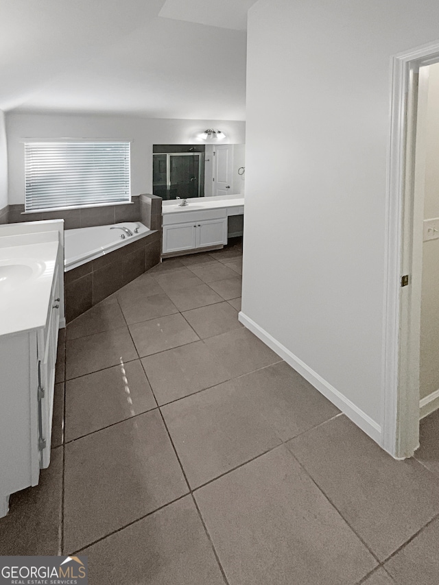 interior space featuring tile patterned flooring, a relaxing tiled tub, and vanity