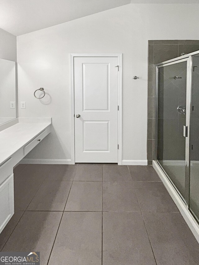 bathroom featuring tile patterned flooring, vanity, lofted ceiling, and walk in shower