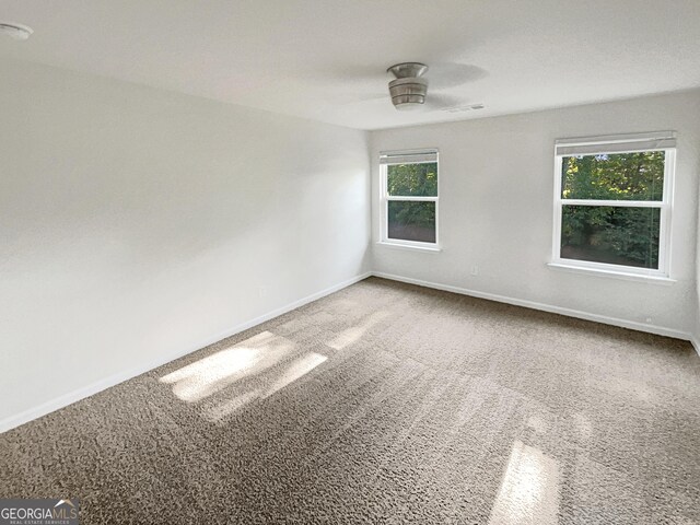 unfurnished room with carpet floors, a wealth of natural light, and ceiling fan