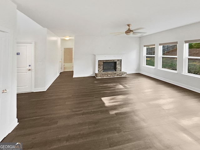 unfurnished living room featuring ceiling fan, dark hardwood / wood-style floors, and a brick fireplace