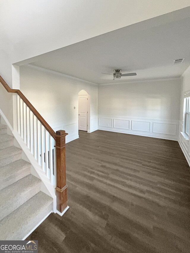 unfurnished living room featuring ceiling fan, crown molding, and dark wood-type flooring