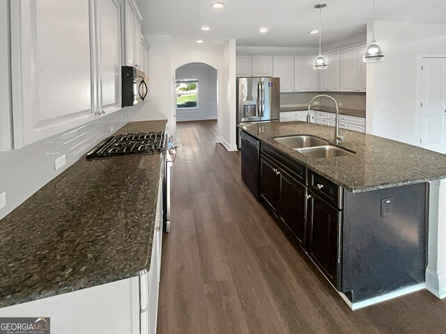 kitchen featuring appliances with stainless steel finishes, sink, a center island with sink, white cabinets, and wood-type flooring