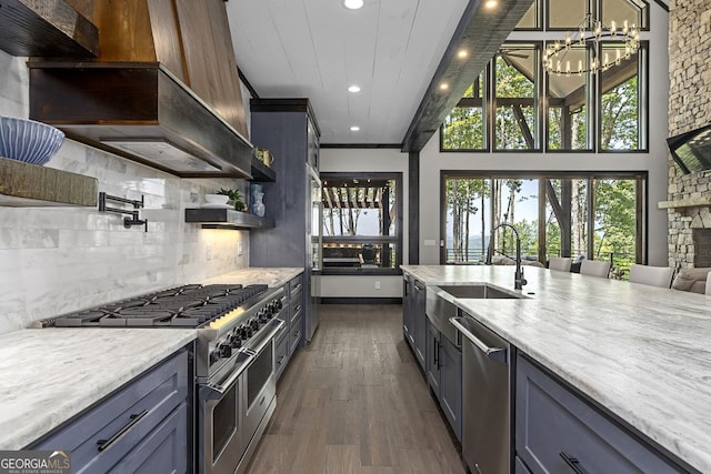 kitchen featuring light stone counters, appliances with stainless steel finishes, dark hardwood / wood-style floors, a stone fireplace, and sink