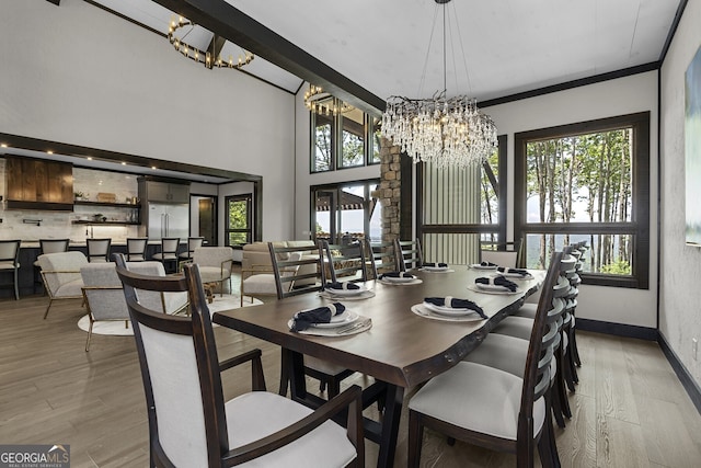 dining area featuring a high ceiling, light hardwood / wood-style flooring, an inviting chandelier, and plenty of natural light