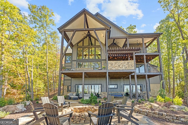 back of property featuring a patio, ceiling fan, a deck, and a fire pit