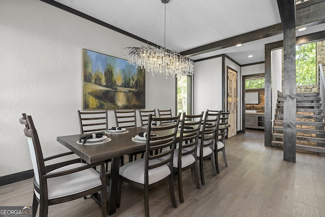 dining room featuring wood-type flooring, ornamental molding, and an inviting chandelier