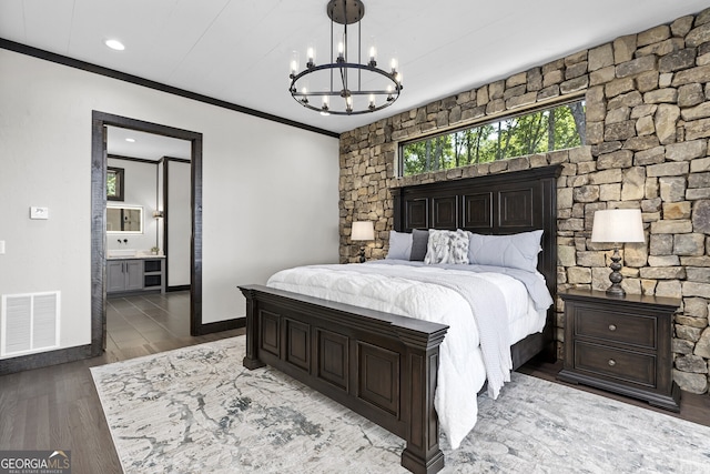 bedroom featuring ornamental molding, hardwood / wood-style floors, a chandelier, and connected bathroom