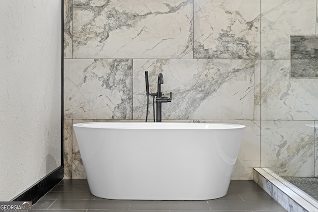 bathroom featuring a bath and tile walls