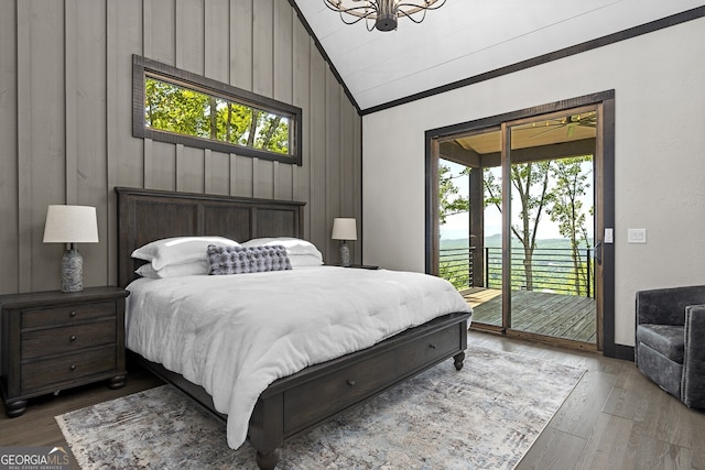 bedroom with access to outside, hardwood / wood-style floors, wood walls, and vaulted ceiling