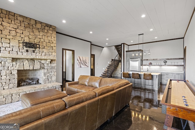 living room with crown molding, a stone fireplace, and bar