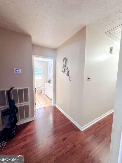 hallway with a textured ceiling and hardwood / wood-style flooring