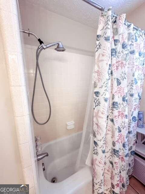 bathroom featuring shower / bath combo and a textured ceiling