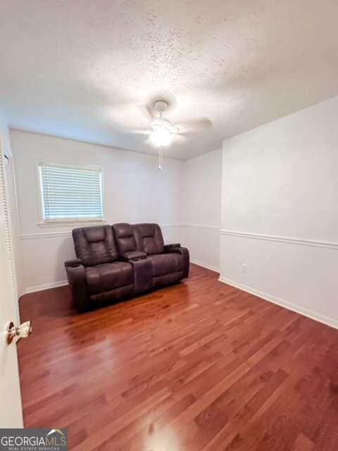 living room with wood-type flooring, ceiling fan, and a textured ceiling