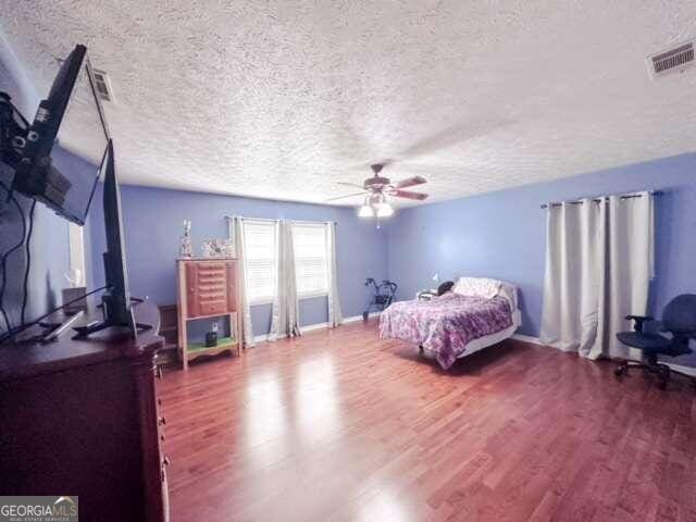 bedroom featuring hardwood / wood-style floors, a textured ceiling, and ceiling fan