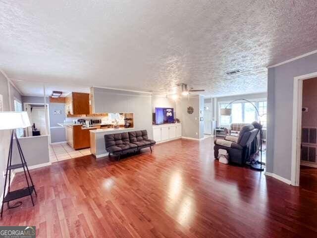 living room with a textured ceiling, light hardwood / wood-style flooring, and ornamental molding