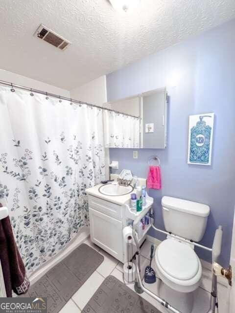 bathroom featuring toilet, vanity, a textured ceiling, and tile patterned floors