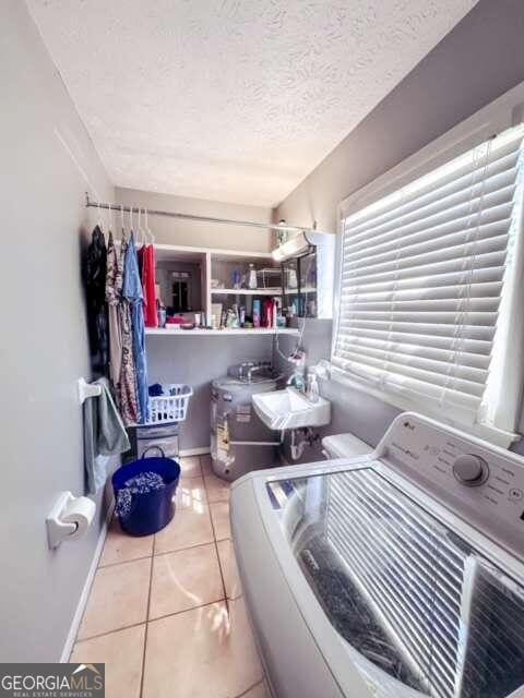 laundry room featuring a textured ceiling, light tile patterned floors, and washer / clothes dryer