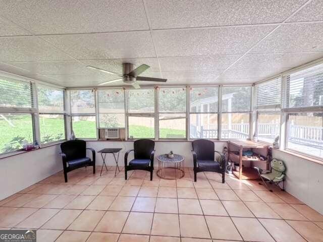 sunroom featuring ceiling fan, cooling unit, and a drop ceiling