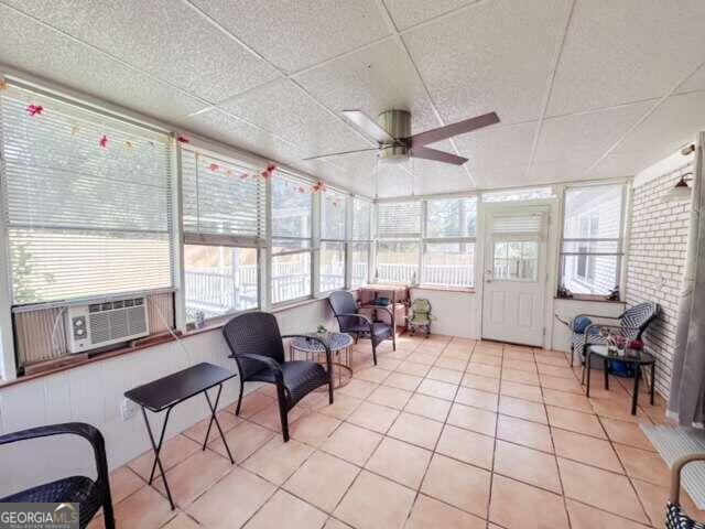 sunroom featuring a drop ceiling, cooling unit, and ceiling fan