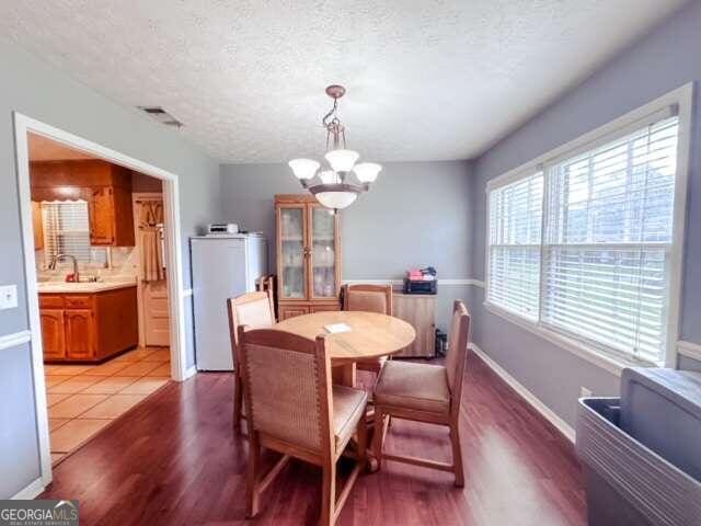 dining room featuring hardwood / wood-style floors, a chandelier, and a textured ceiling