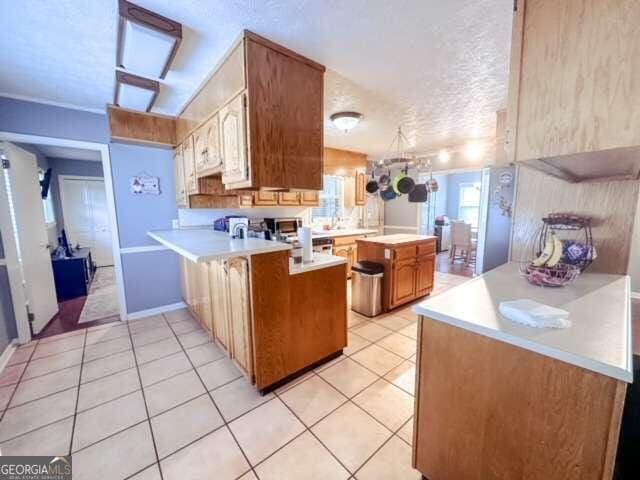 kitchen featuring kitchen peninsula, a textured ceiling, and light tile patterned floors