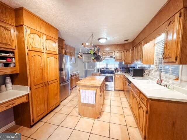 kitchen with a chandelier, appliances with stainless steel finishes, light tile patterned floors, and a center island