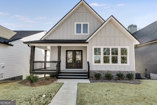 view of front of house featuring a front lawn, central air condition unit, and a porch