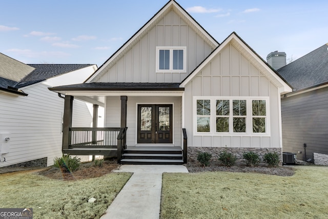 view of front facade featuring board and batten siding, covered porch, a shingled roof, and a front lawn