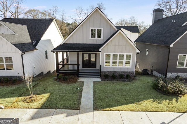 view of front facade with cooling unit, covered porch, and a front lawn