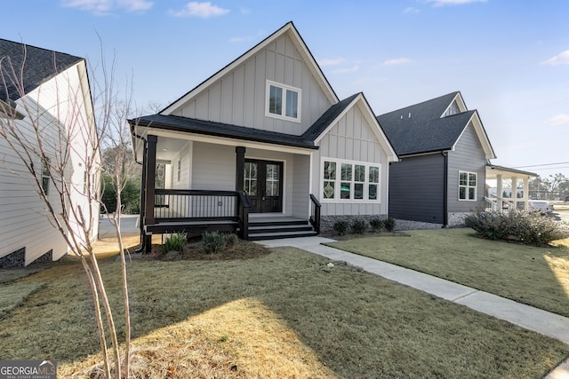 view of front of property with french doors, roof with shingles, a porch, board and batten siding, and a front yard