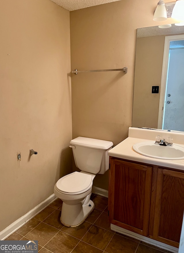 bathroom featuring vanity, toilet, tile patterned floors, and a textured ceiling