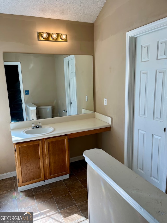 bathroom with tile patterned flooring, toilet, a textured ceiling, and vanity