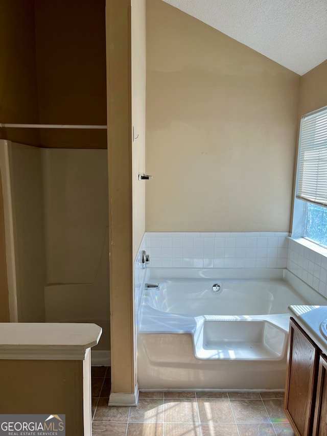 bathroom featuring vanity, a textured ceiling, tile patterned flooring, and a bathtub