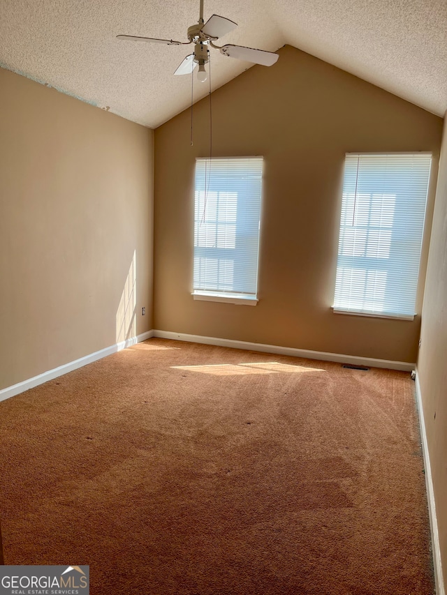 empty room featuring carpet flooring, a textured ceiling, ceiling fan, and lofted ceiling