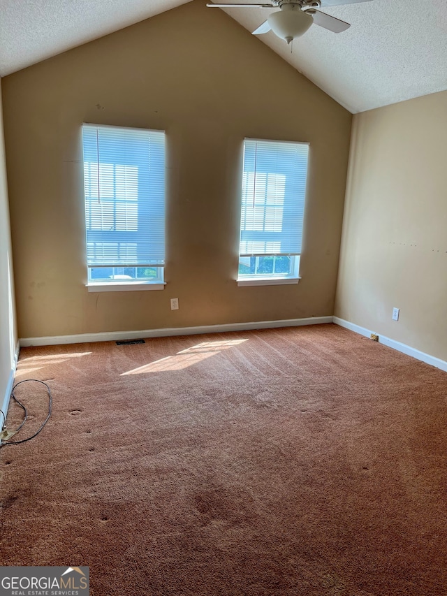 unfurnished room featuring lofted ceiling, a wealth of natural light, ceiling fan, and a textured ceiling