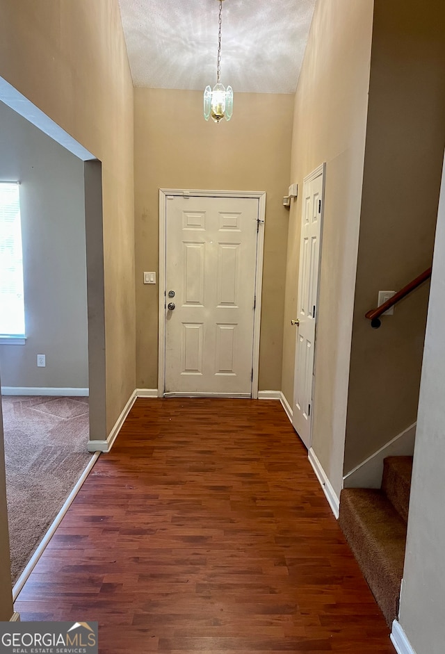 foyer entrance featuring a towering ceiling, a textured ceiling, a chandelier, and dark hardwood / wood-style floors