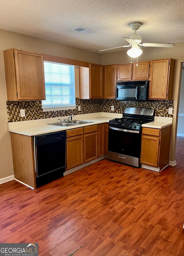 kitchen with a textured ceiling, black appliances, wood-type flooring, sink, and ceiling fan