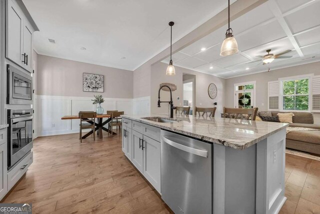 kitchen with a kitchen island with sink, light wood-type flooring, stainless steel appliances, and sink