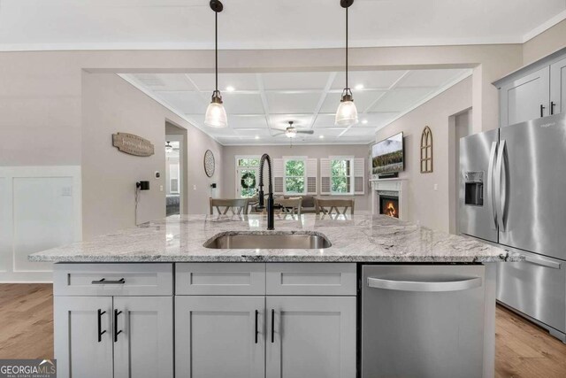 kitchen with appliances with stainless steel finishes, light stone countertops, coffered ceiling, light hardwood / wood-style floors, and sink