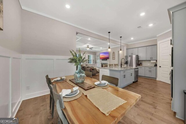 dining area with sink, light hardwood / wood-style flooring, crown molding, and ceiling fan