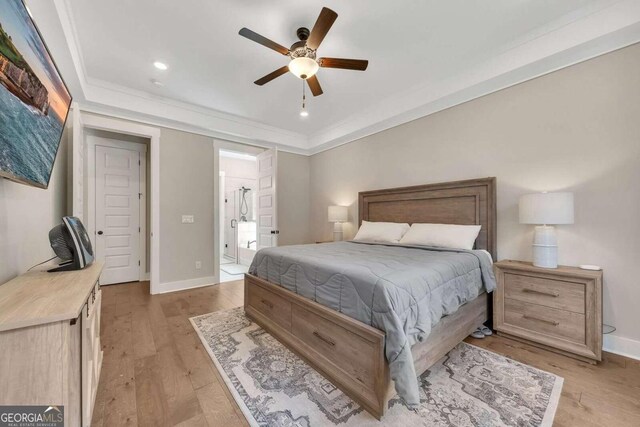 bedroom featuring ceiling fan, ensuite bathroom, ornamental molding, and light hardwood / wood-style floors