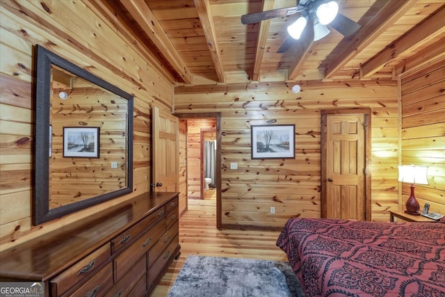 bedroom featuring wood walls, light hardwood / wood-style floors, beamed ceiling, and wooden ceiling