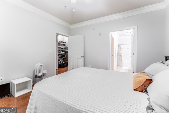 bedroom with wood-type flooring, connected bathroom, and ornamental molding