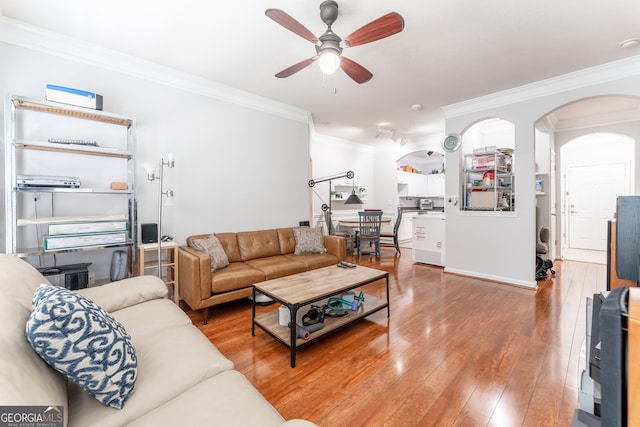 living room featuring wood-type flooring, ceiling fan, and crown molding